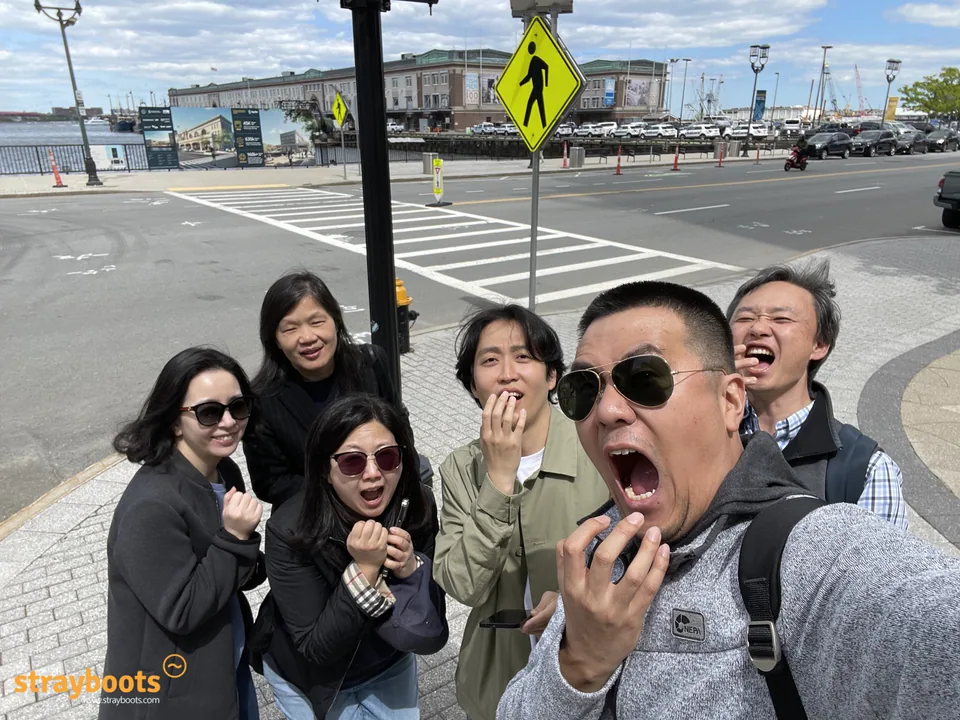 A group makes surprised faces for a selfie on a Boston Seaport street.