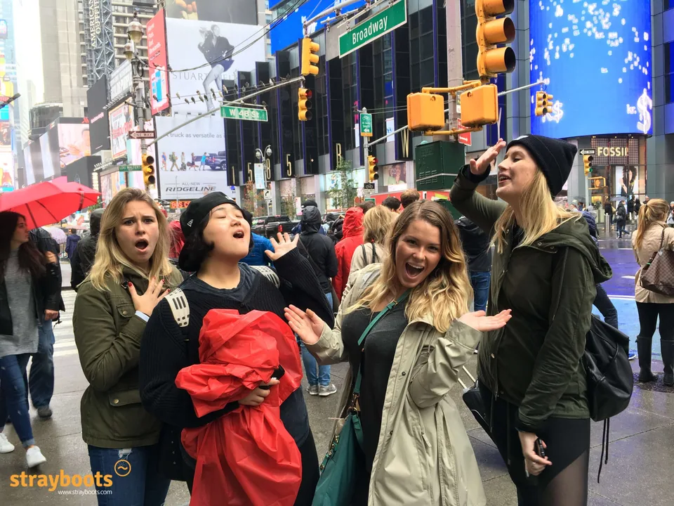 Four participants strike playful poses near Broadway and West 48th Street in Times Square.